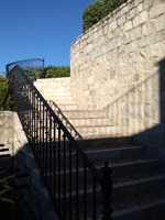 Escalera curba empedrada y muro de sillarejo de piedra caliza